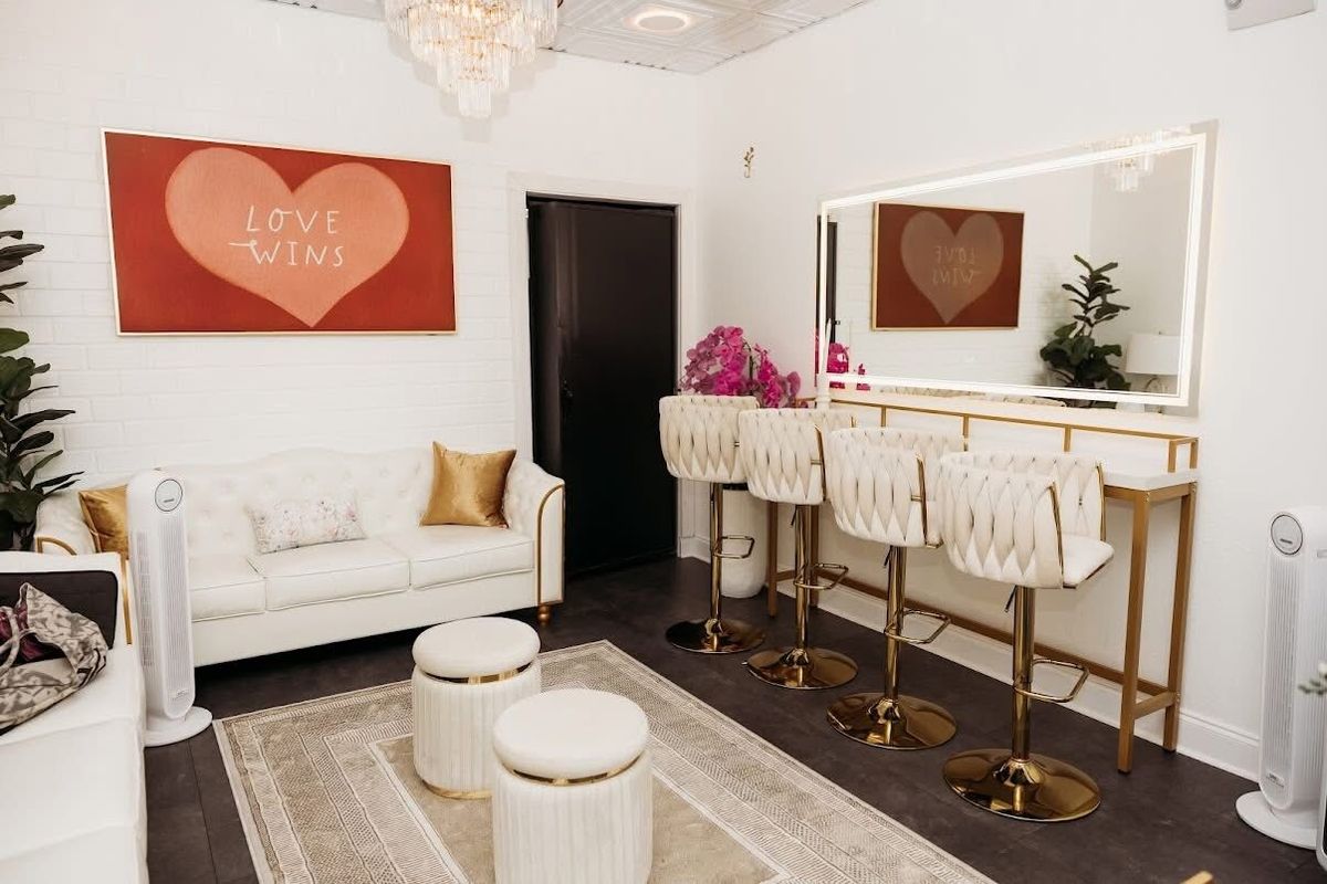 The white and gold VIP Suite at Trellis 925, with a tufted sofa, vanity stools and a lit mirror