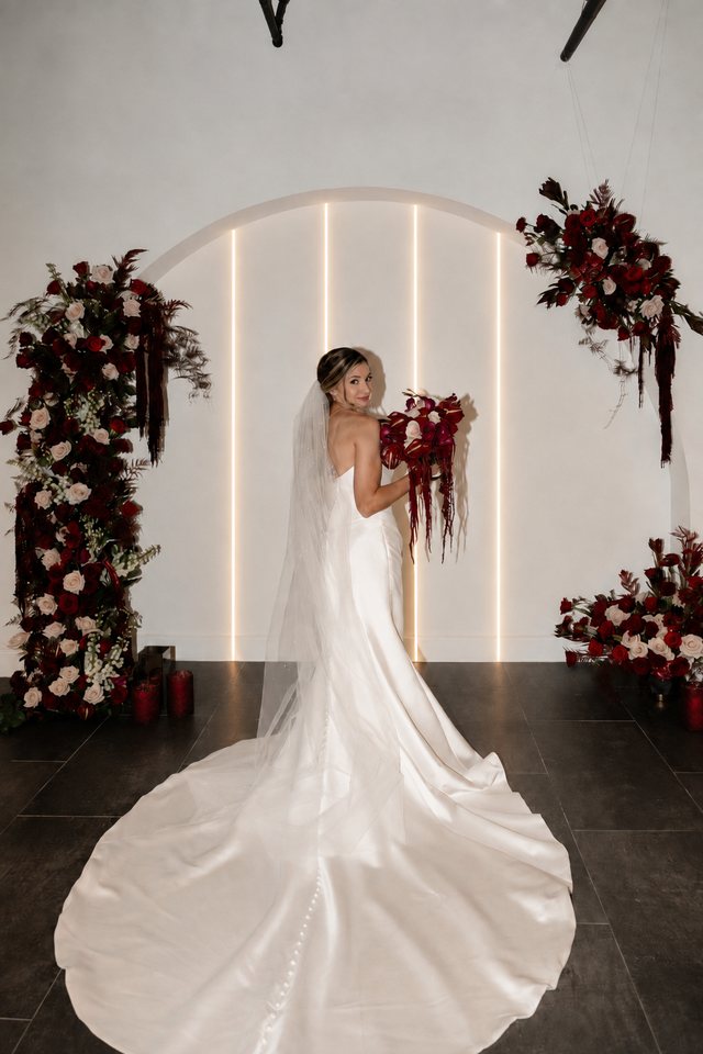 A bride beside the floral ceremony arch at Trellis 925