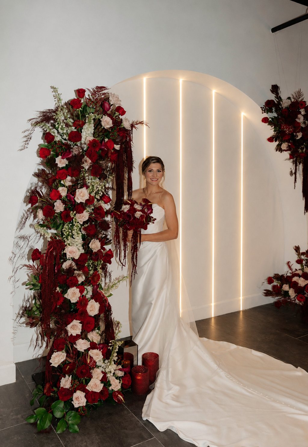 A bride beside deep red ceremony florals at Trellis 925