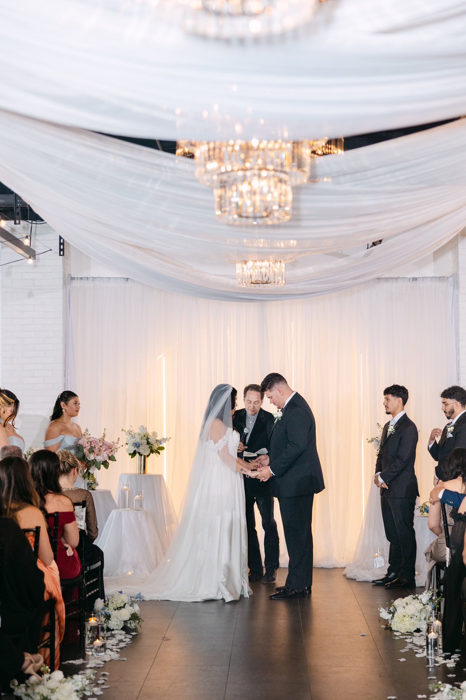 A ceremony beneath white drapery and chandeliers at Trellis 925