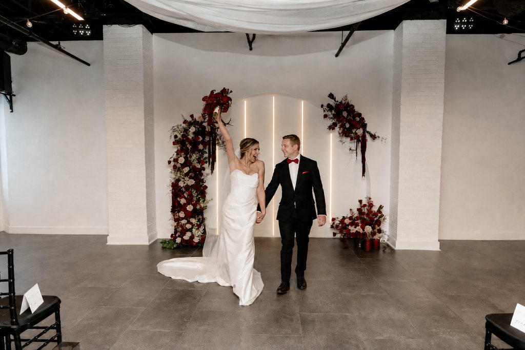 A newly married couple beneath the floral arch at Trellis 925